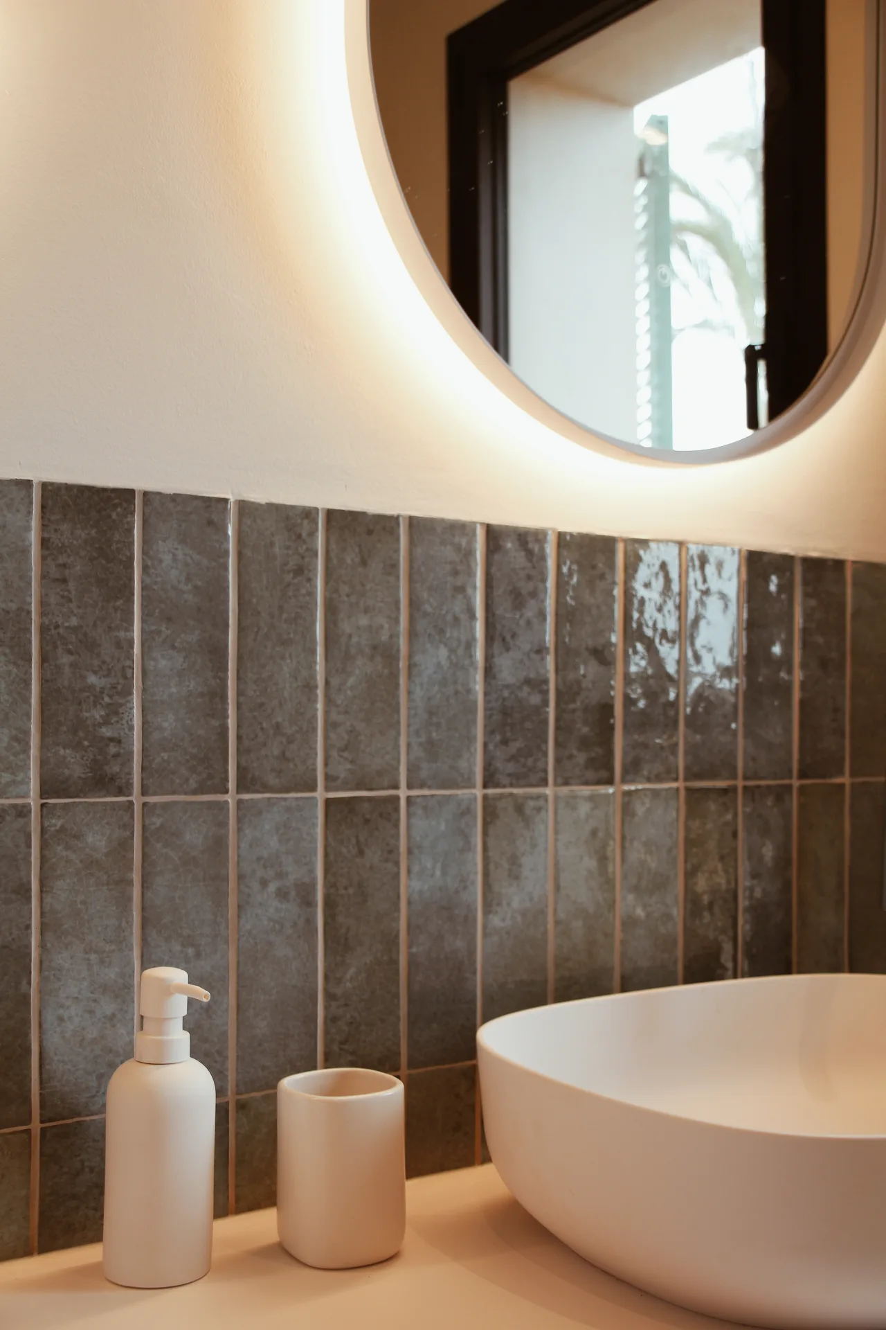 Baño con bañera exenta, azulejo verde y espejo redondo retroiluminado Baño con bañera exenta, azulejo verde y espejo redondo retroiluminado