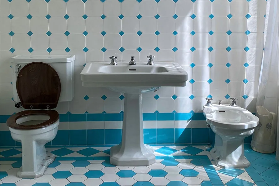 Classic bathroom with turquoise and white tiles and pedestal fittings before the renovation
