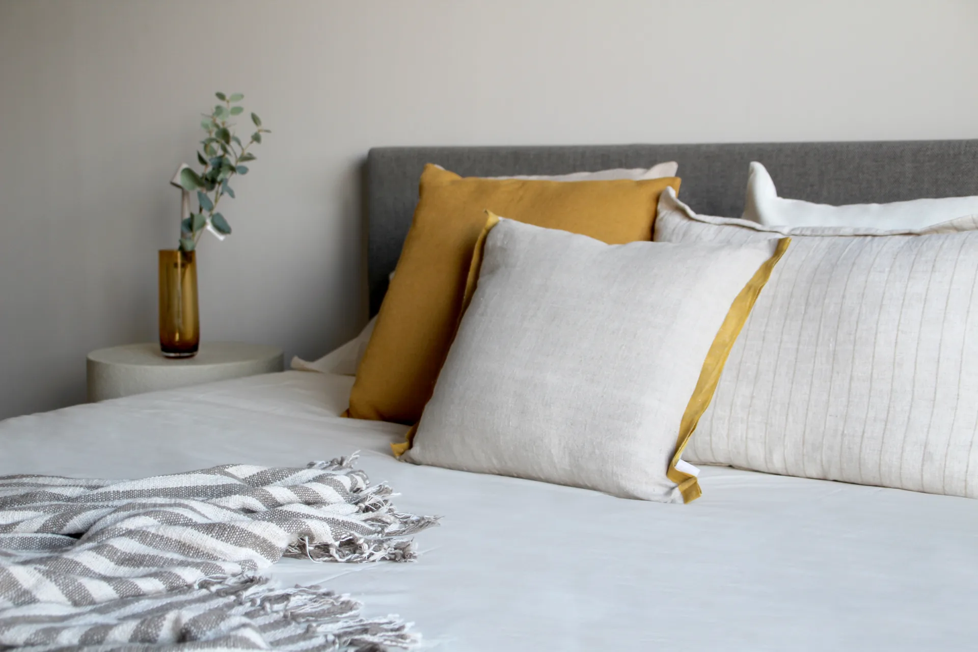 Cama con cojines mostaza y blancos en un dormitorio de Campanet Cama con cojines mostaza y blancos en un dormitorio de Campanet