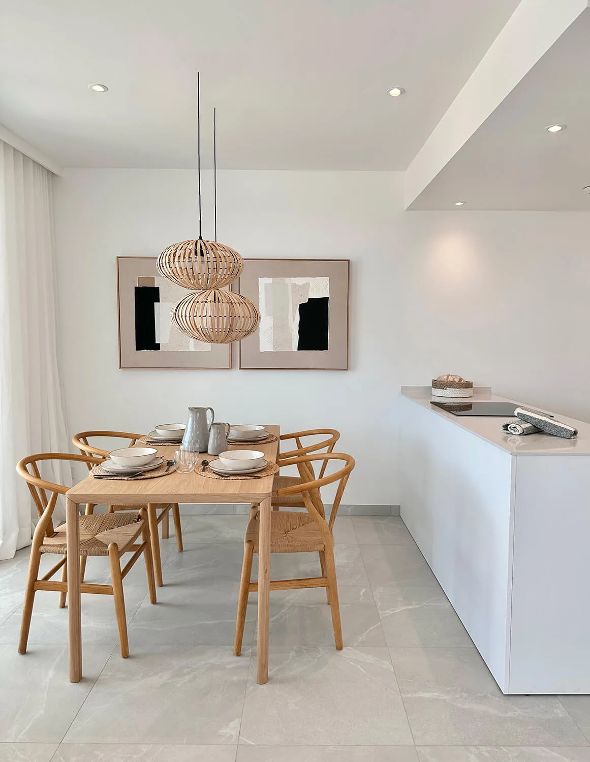 Comedor con lámparas de fibra y cuadros abstractos en un apartamento de Cala d'Or