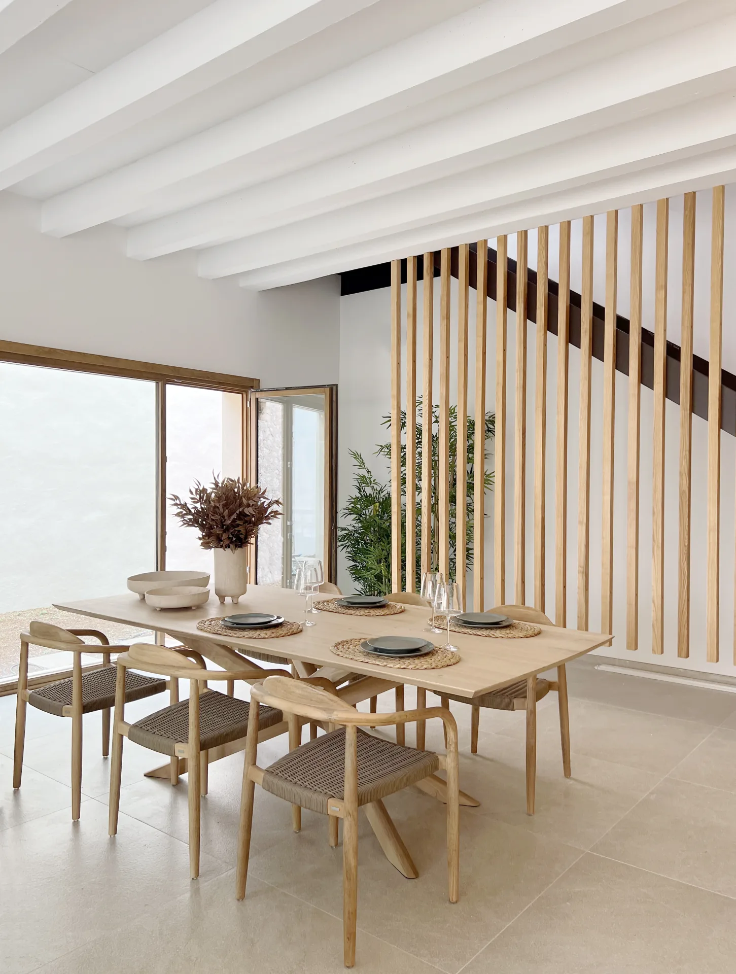 Comedor con mesa de madera junto a la escalera de listones