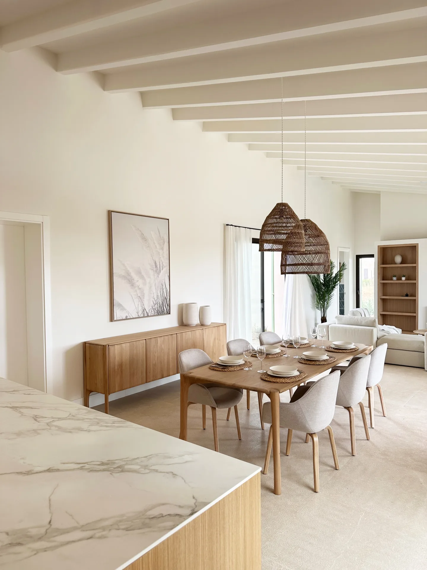 Comedor con mesa de madera y lámpara de fibra bajo techo de vigas blancas Comedor con mesa de madera y lámpara de fibra bajo techo de vigas blancas
