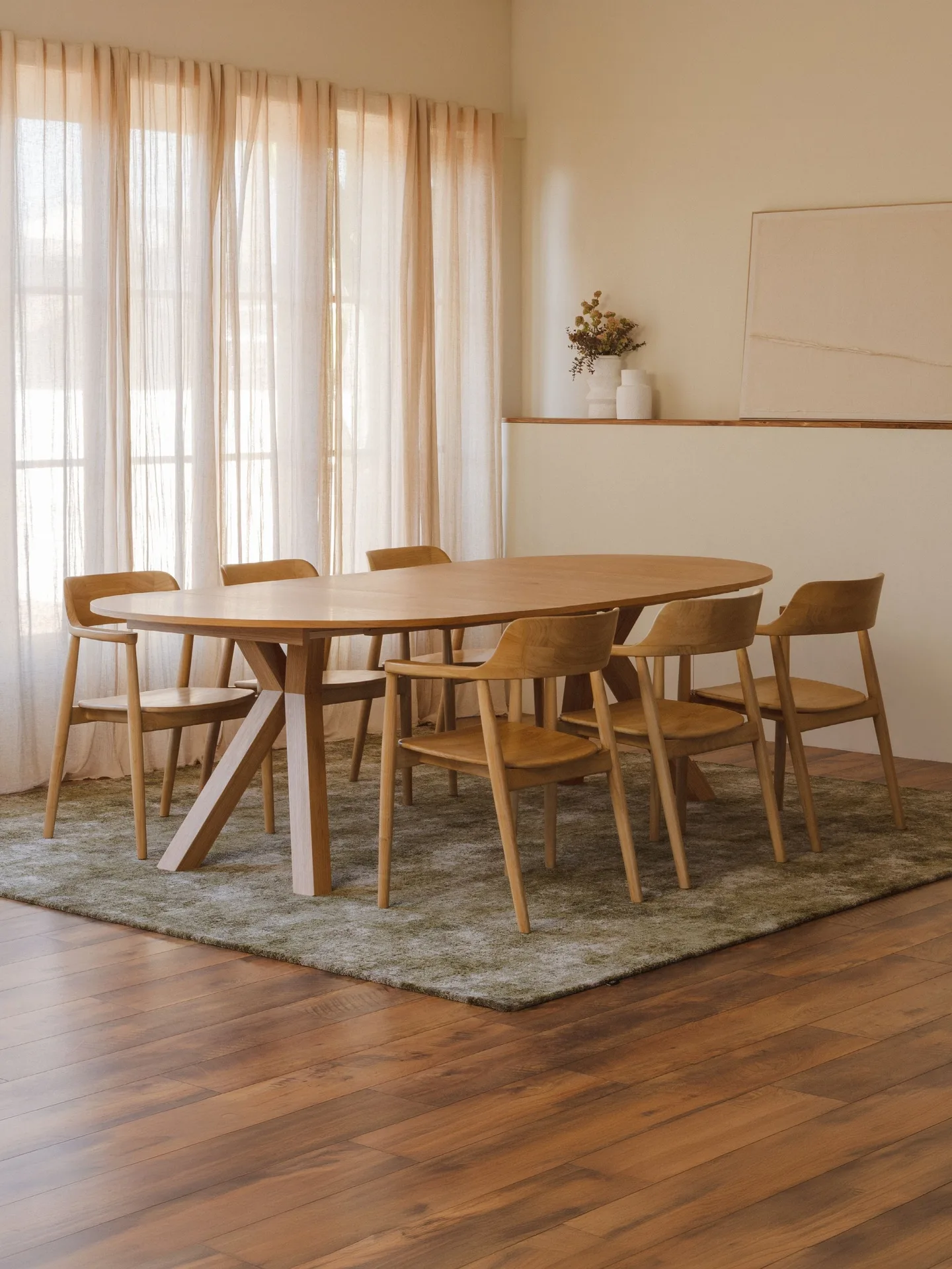 Comedor con mesa ovalada de madera y sillas junto a ventanales con cortinas Comedor con mesa ovalada de madera y sillas junto a ventanales con cortinas
