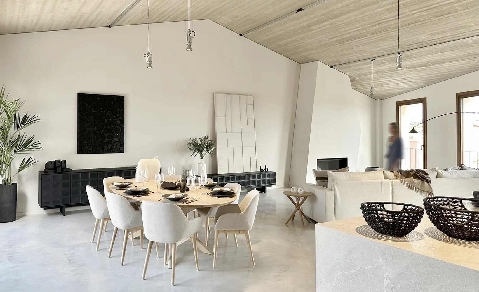 Comedor con mesa redonda y sillas blancas bajo un techo de madera en la vivienda de obra nueva de Campanet