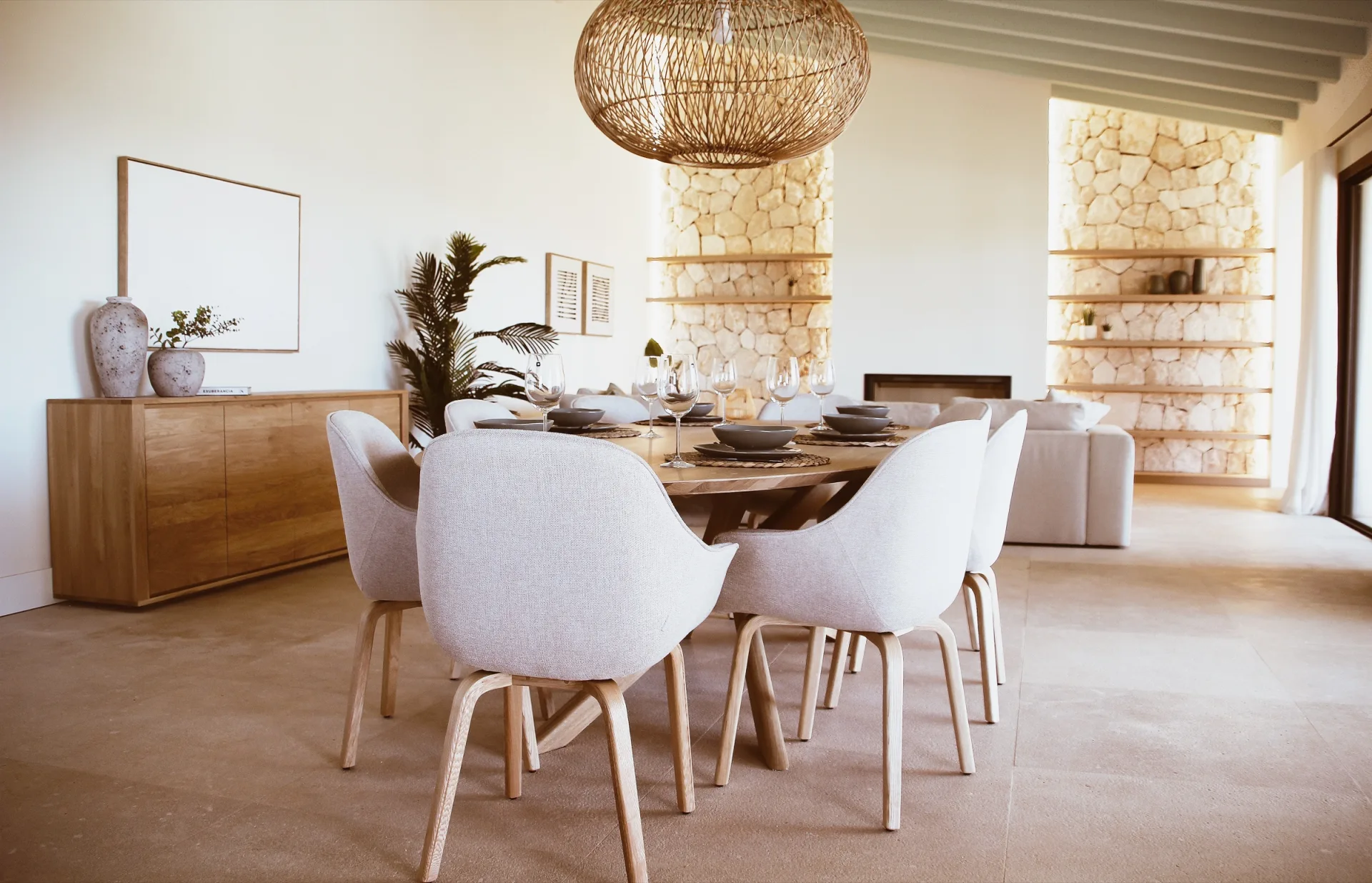 Comedor con sillas tapizadas bajo lámpara de fibra y pared de piedra Comedor con sillas tapizadas bajo lámpara de fibra y pared de piedra