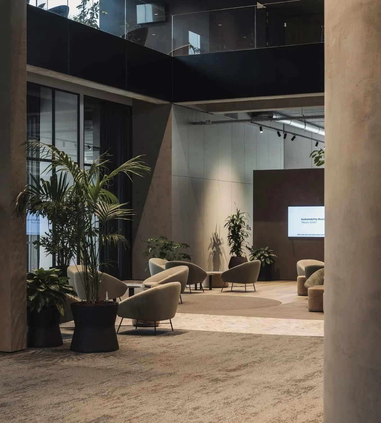 contract-lobby-oficinas-zona-espera Zona de espera de oficinas con butacas tapizadas, plantas y columnas de hormigón