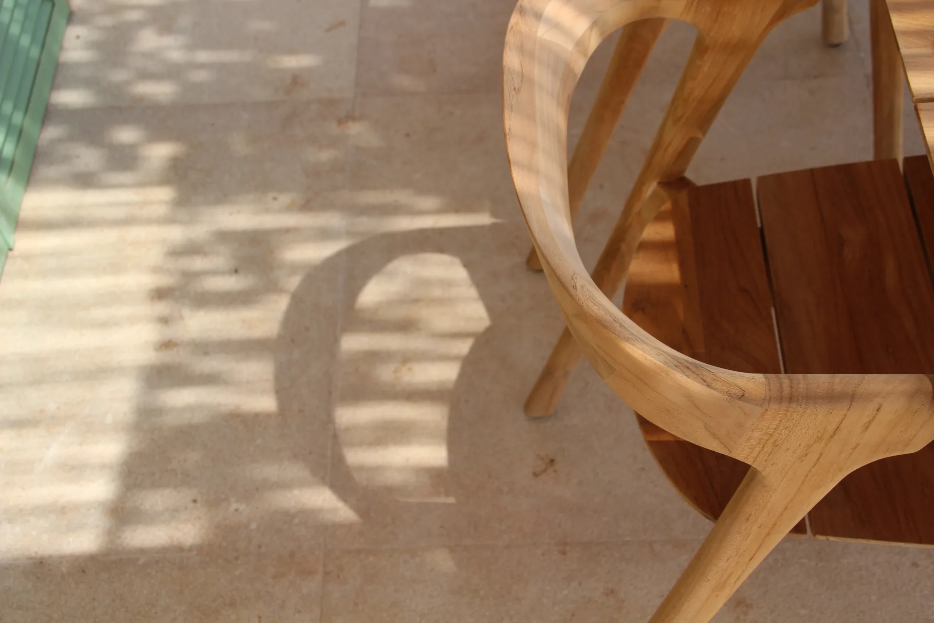 Detalle de silla de madera con sombras de pérgola Detalle de silla de madera con sombras de pérgola