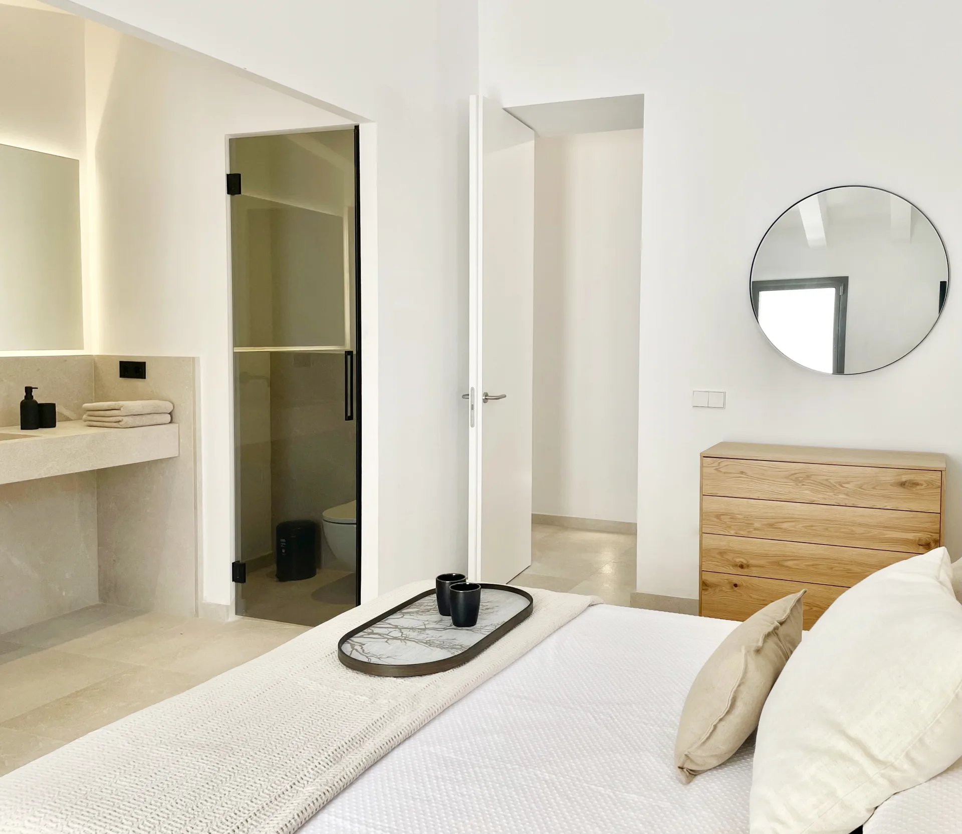 Dormitorio con bandeja sobre la cama y espejo redondo Dormitorio con bandeja sobre la cama y espejo redondo