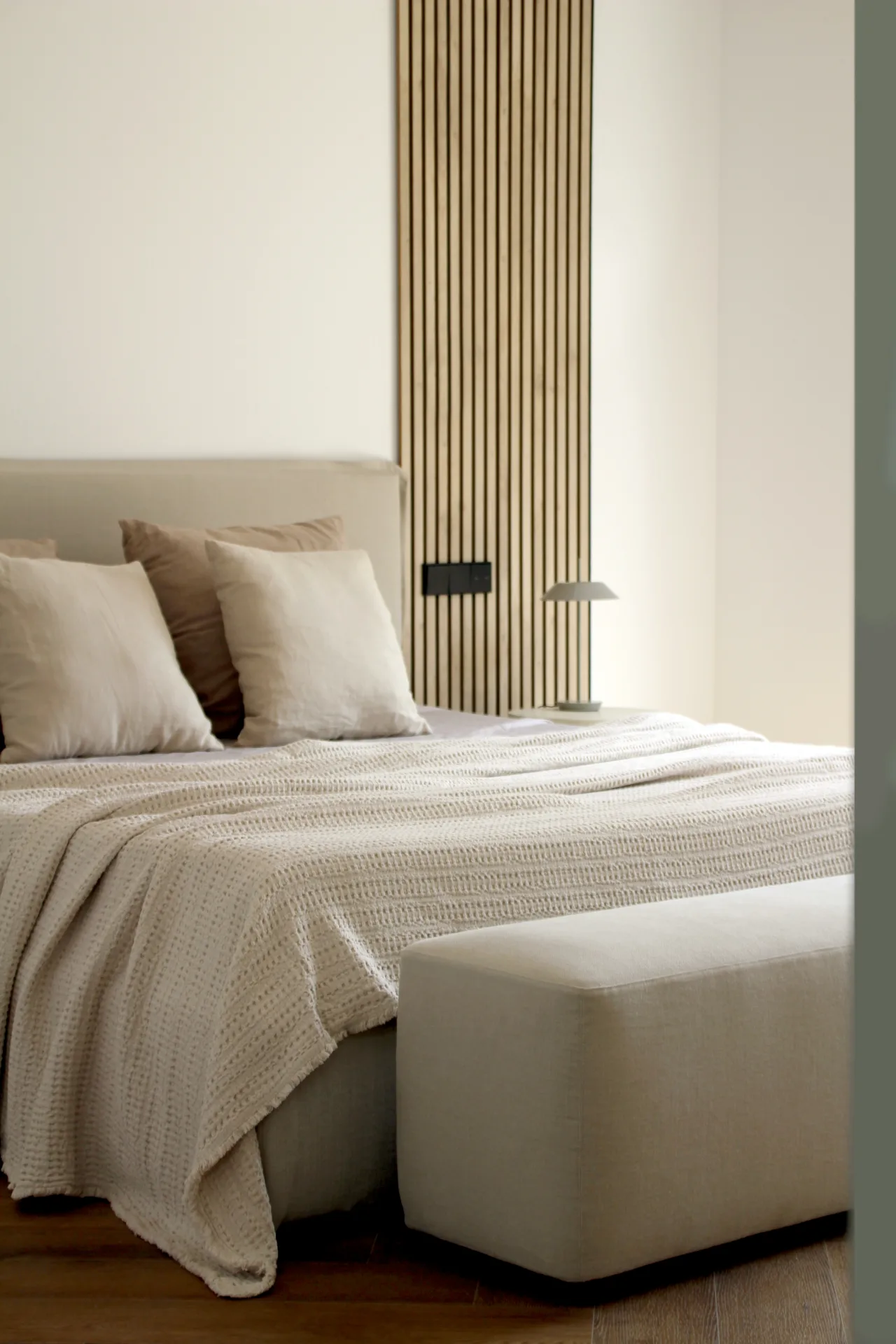 Dormitorio con panel de listones de madera y banco a los pies de la cama Dormitorio con panel de listones de madera y banco a los pies de la cama