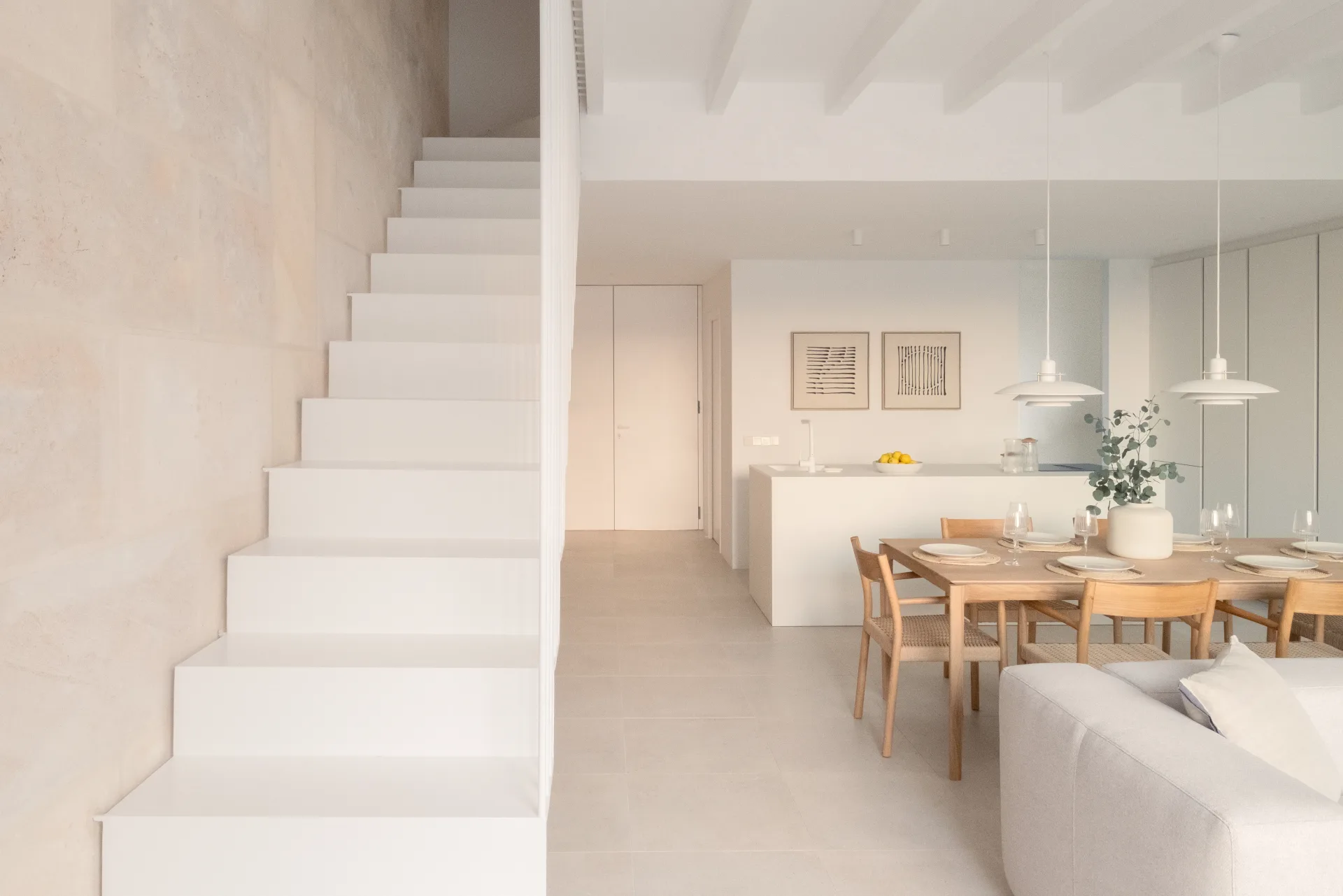 White staircase and open kitchen-dining area in a home in Ariany, Mallorca