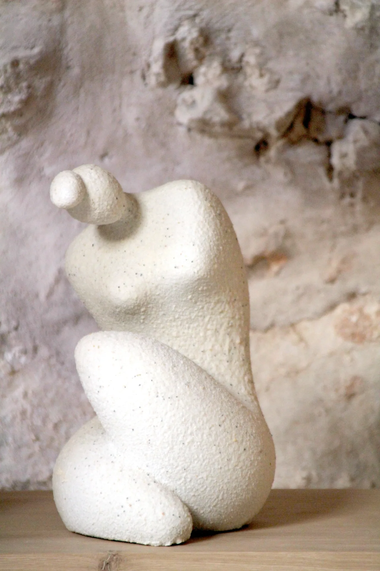 Escultura blanca frente a una pared de piedra Escultura blanca frente a una pared de piedra