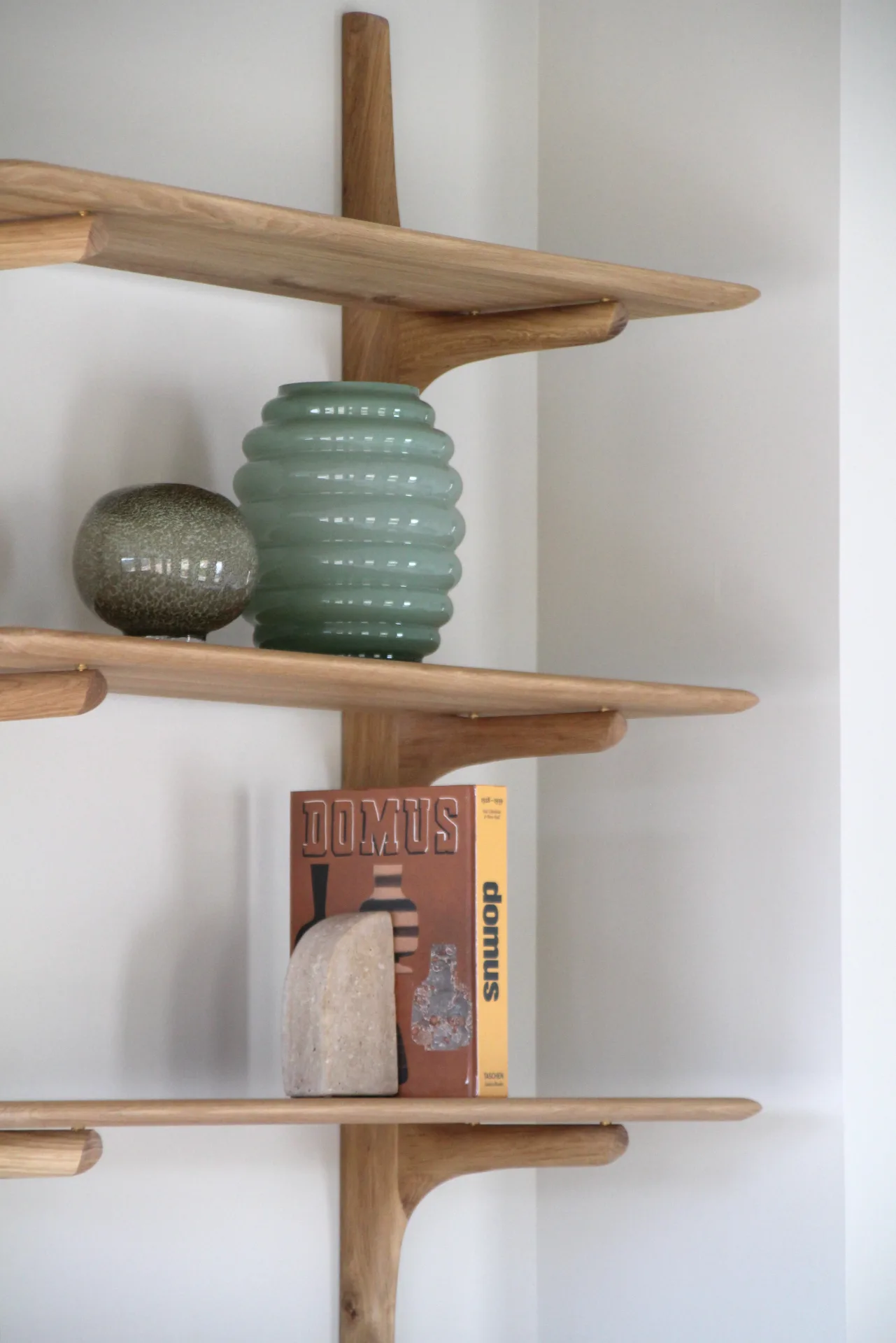 Estantería de madera con jarrón verde de cerámica y libros Estantería de madera con jarrón verde de cerámica y libros