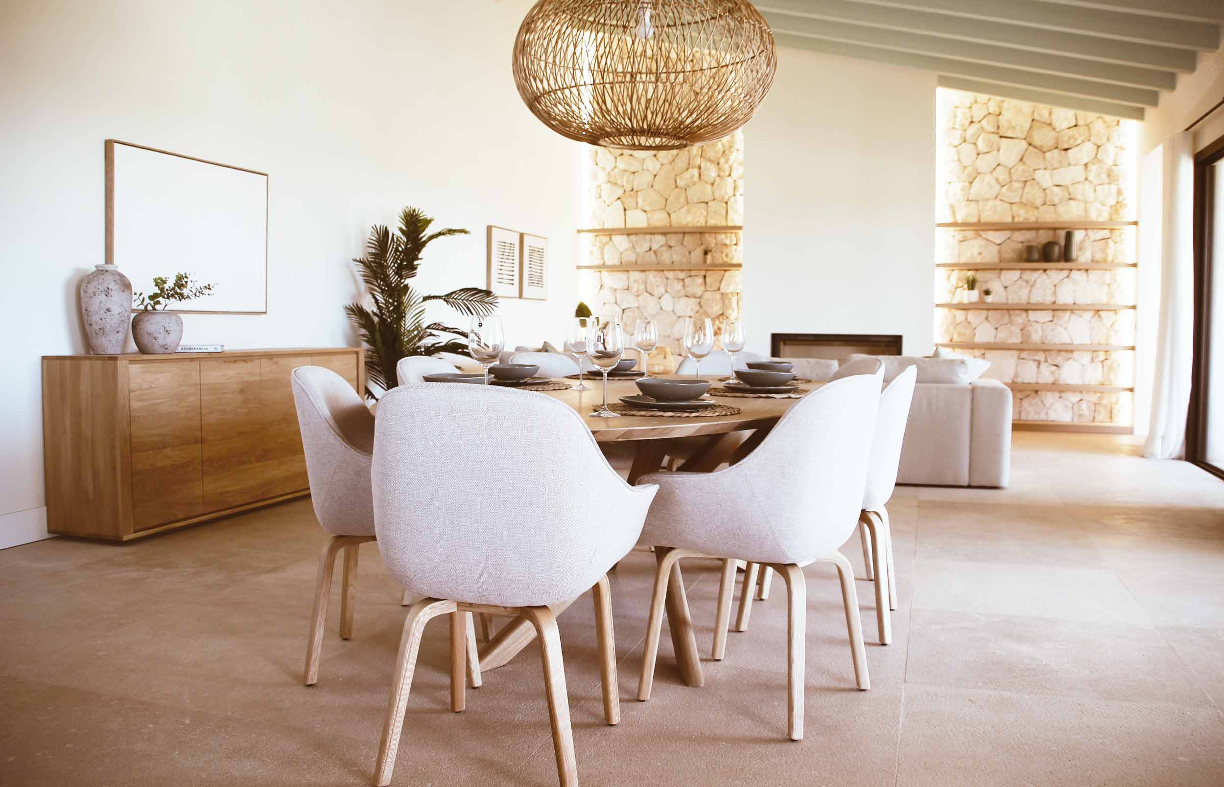 estela-maris-project Comedor con mesa redonda de madera, sillas tapizadas y lámpara de fibra en la vivienda Estela Maris de Sa Ràpita