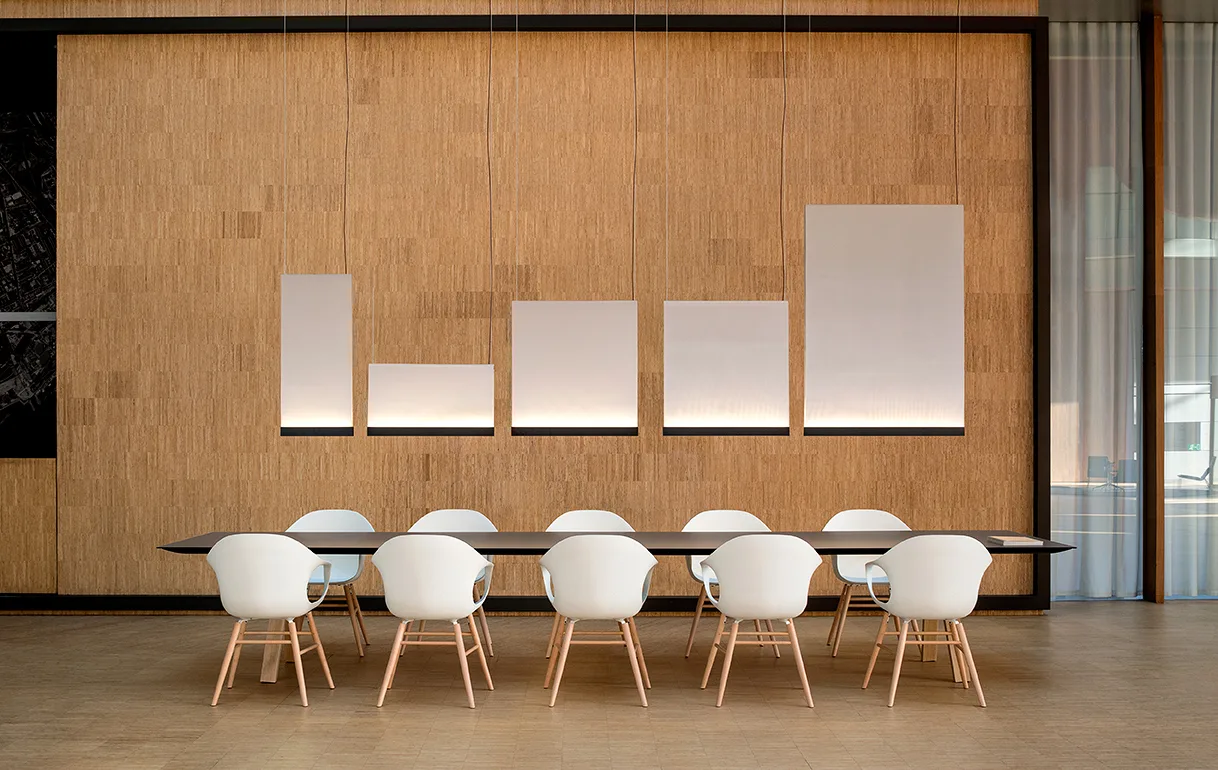 Esstisch mit weißen Stühlen vor einer Holzwand mit Vibia Wandleuchten