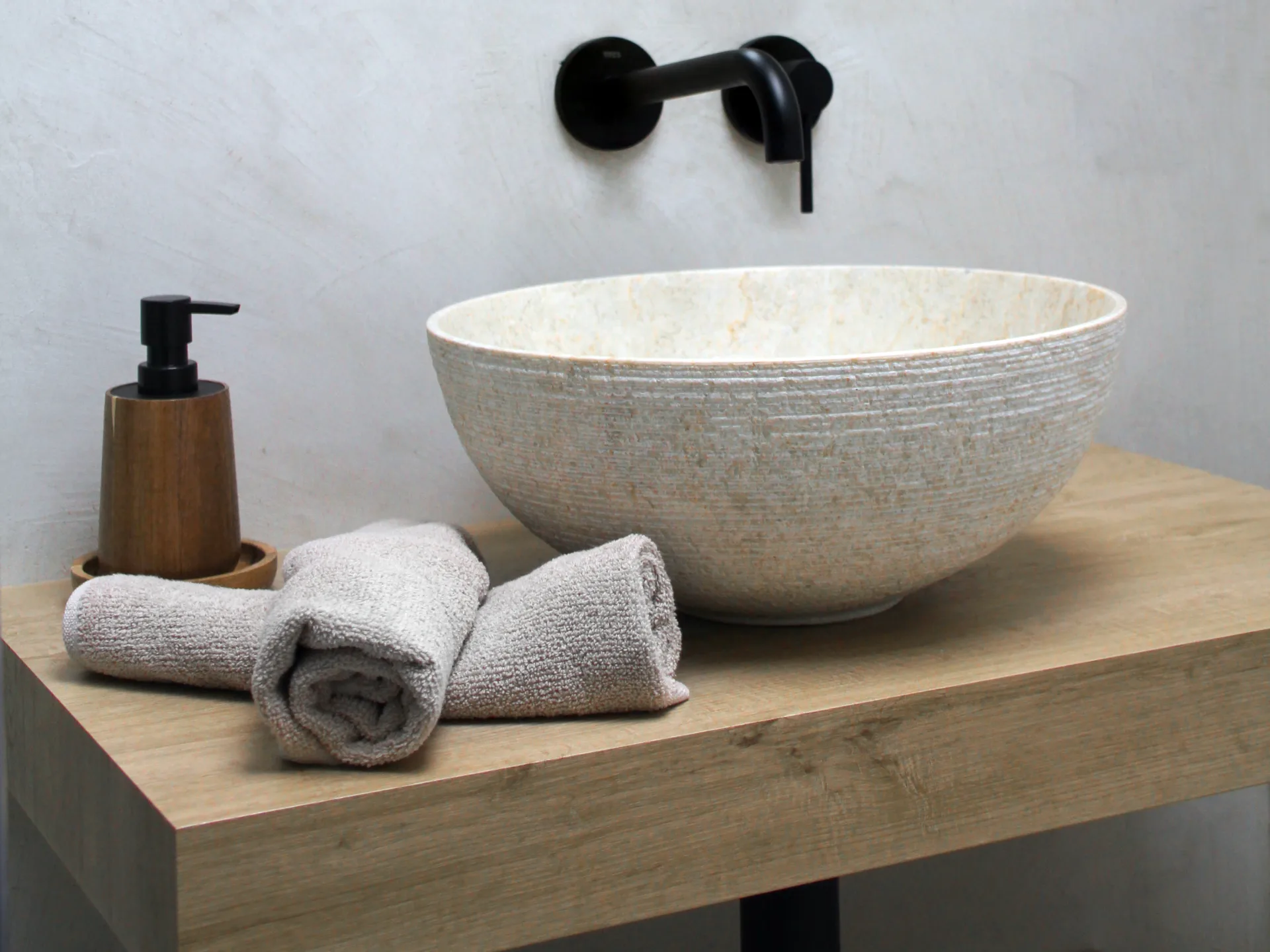Lavabo de piedra sobre encimera de madera con grifería negra Lavabo de piedra sobre encimera de madera con grifería negra