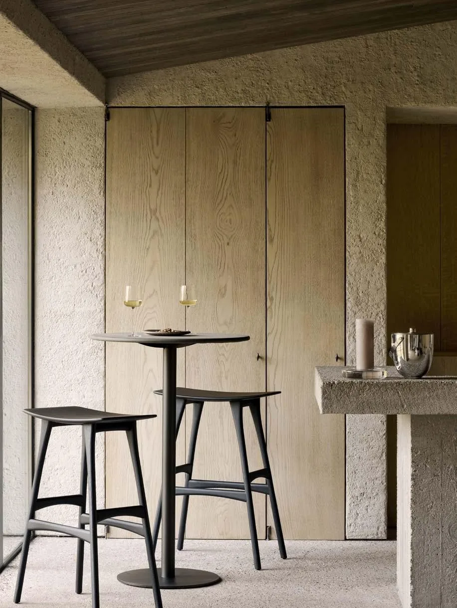 Mesa alta con taburetes de madera en un espacio de hostelería