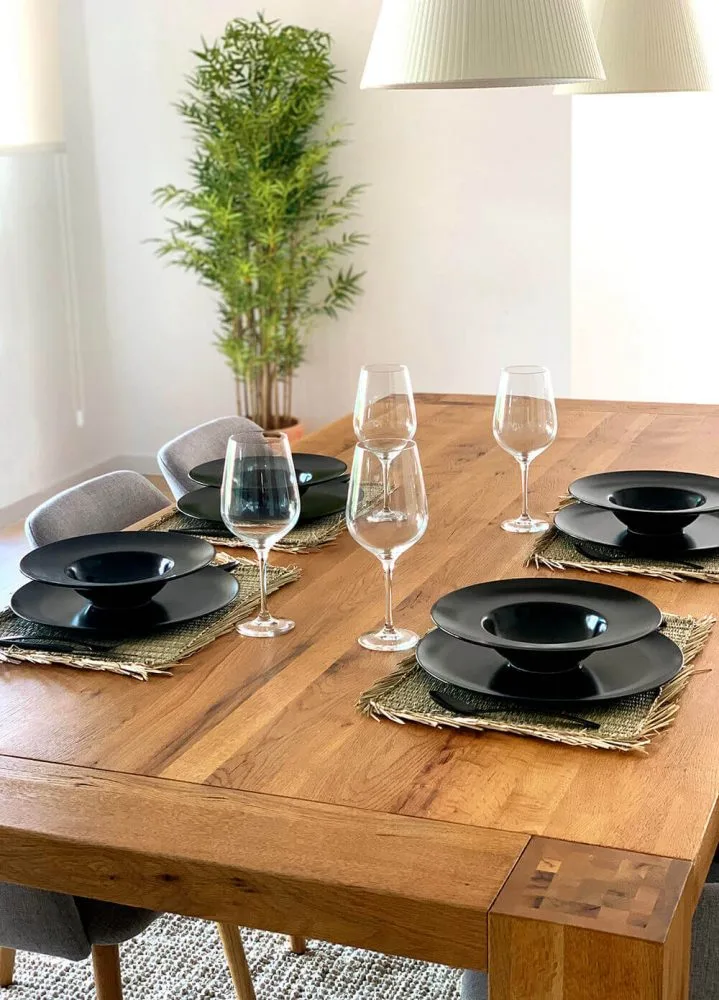 Mesa de comedor de madera con copas y platos negros Mesa de comedor de madera con copas y platos negros