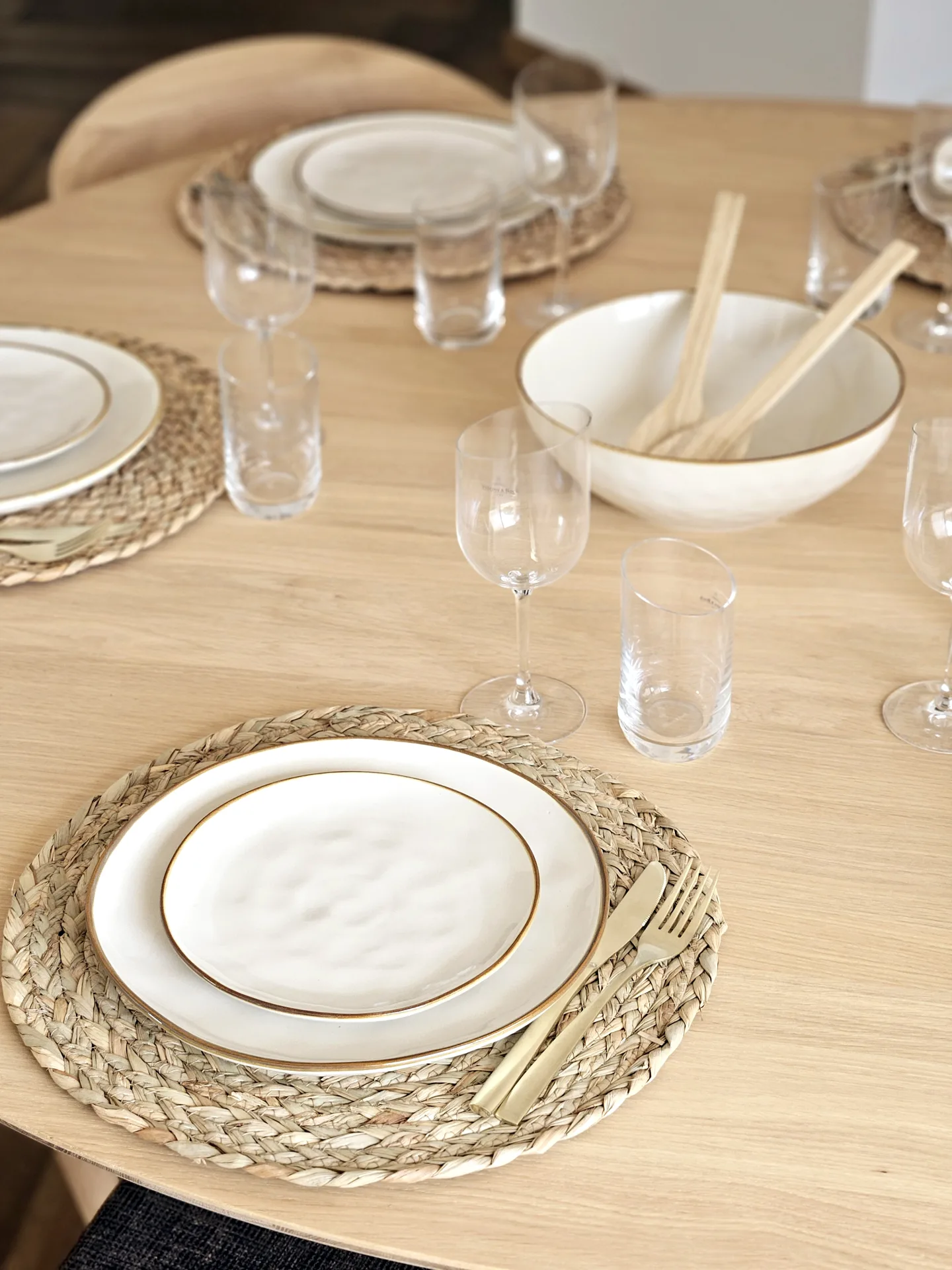 Mesa de comedor puesta con platos blancos y bajoplatos de fibra Mesa de comedor puesta con platos blancos y bajoplatos de fibra