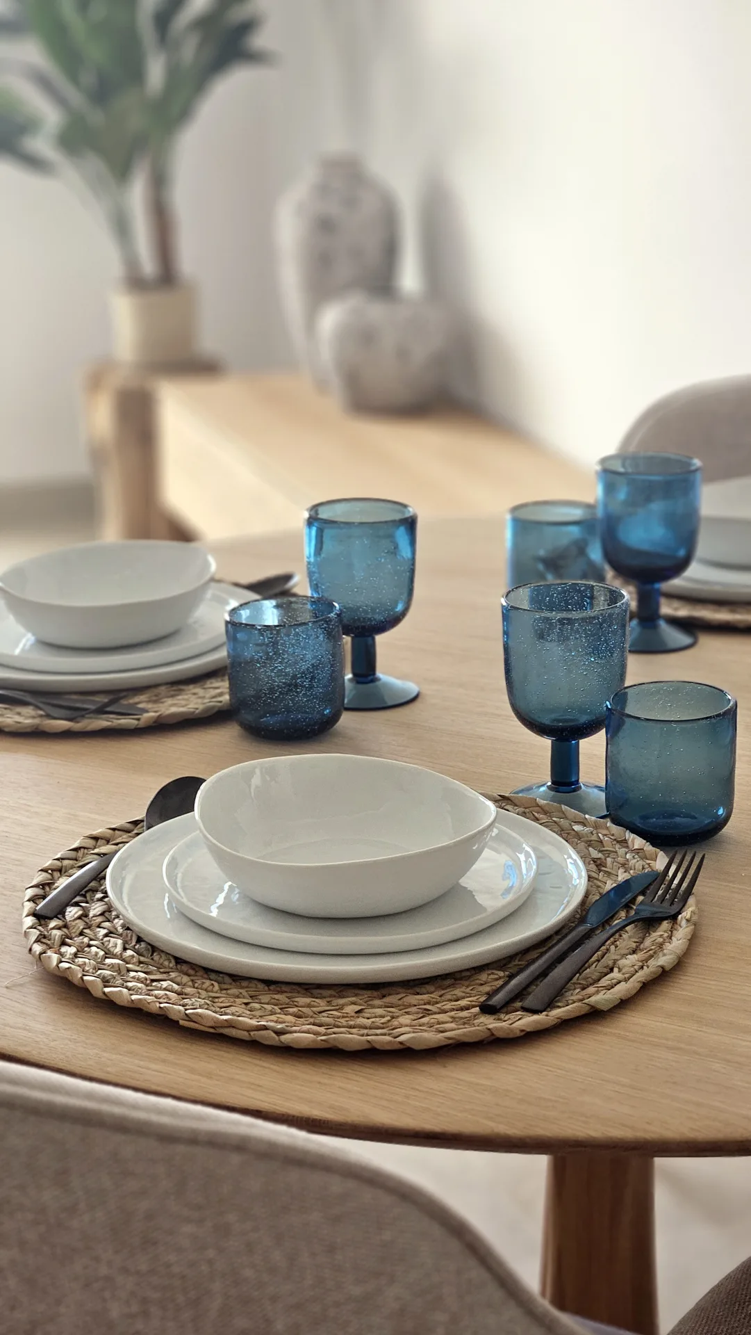 Mesa de comedor puesta con vasos azules y platos blancos en Cala d'Or