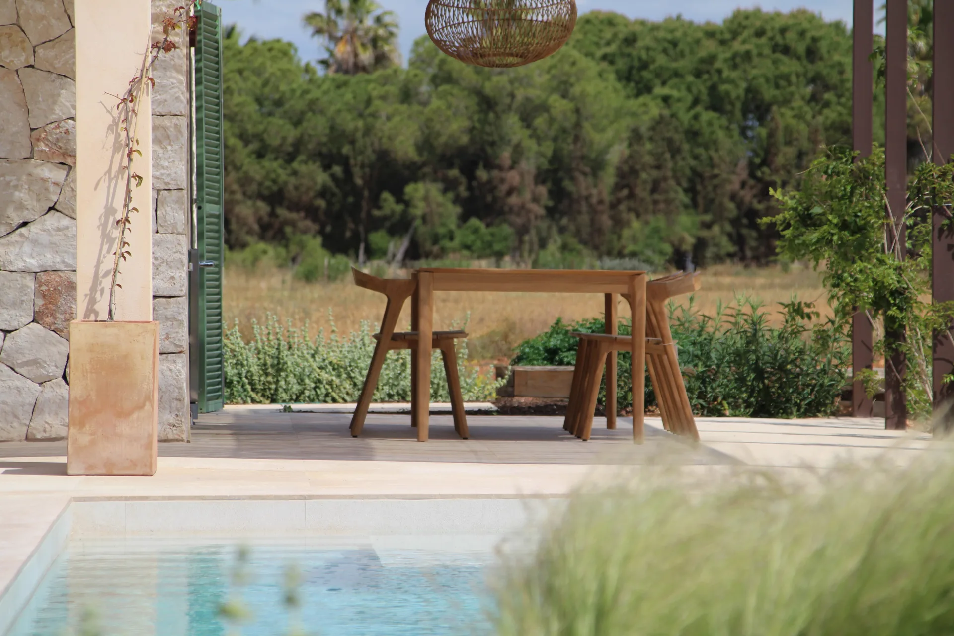 Mesa de exterior de madera junto a la piscina y el pinar Mesa de exterior de madera junto a la piscina y el pinar