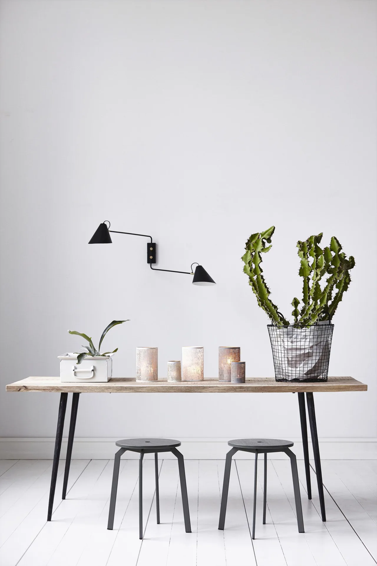 Nordic-style wooden table with black stools and wall lamps