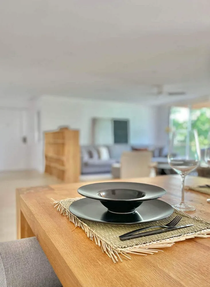 Mesa de madera puesta con platos negros Mesa de madera puesta con platos negros