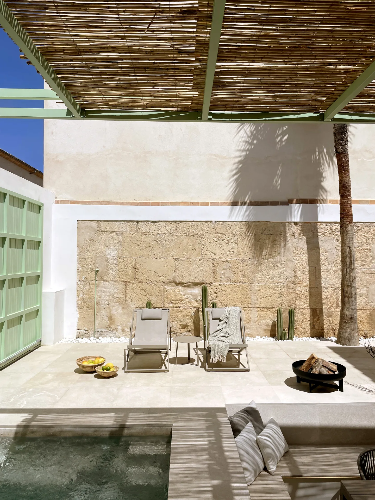 Patio con pérgola de cañizo y tumbonas junto a la piscina