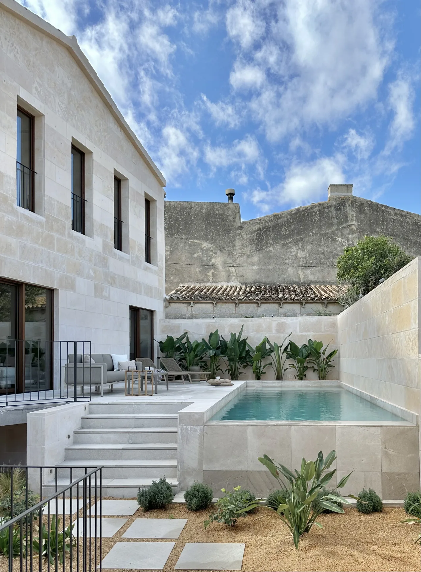 Patio con piscina y fachada de piedra de una vivienda en Campanet Patio con piscina y fachada de piedra de una vivienda en Campanet