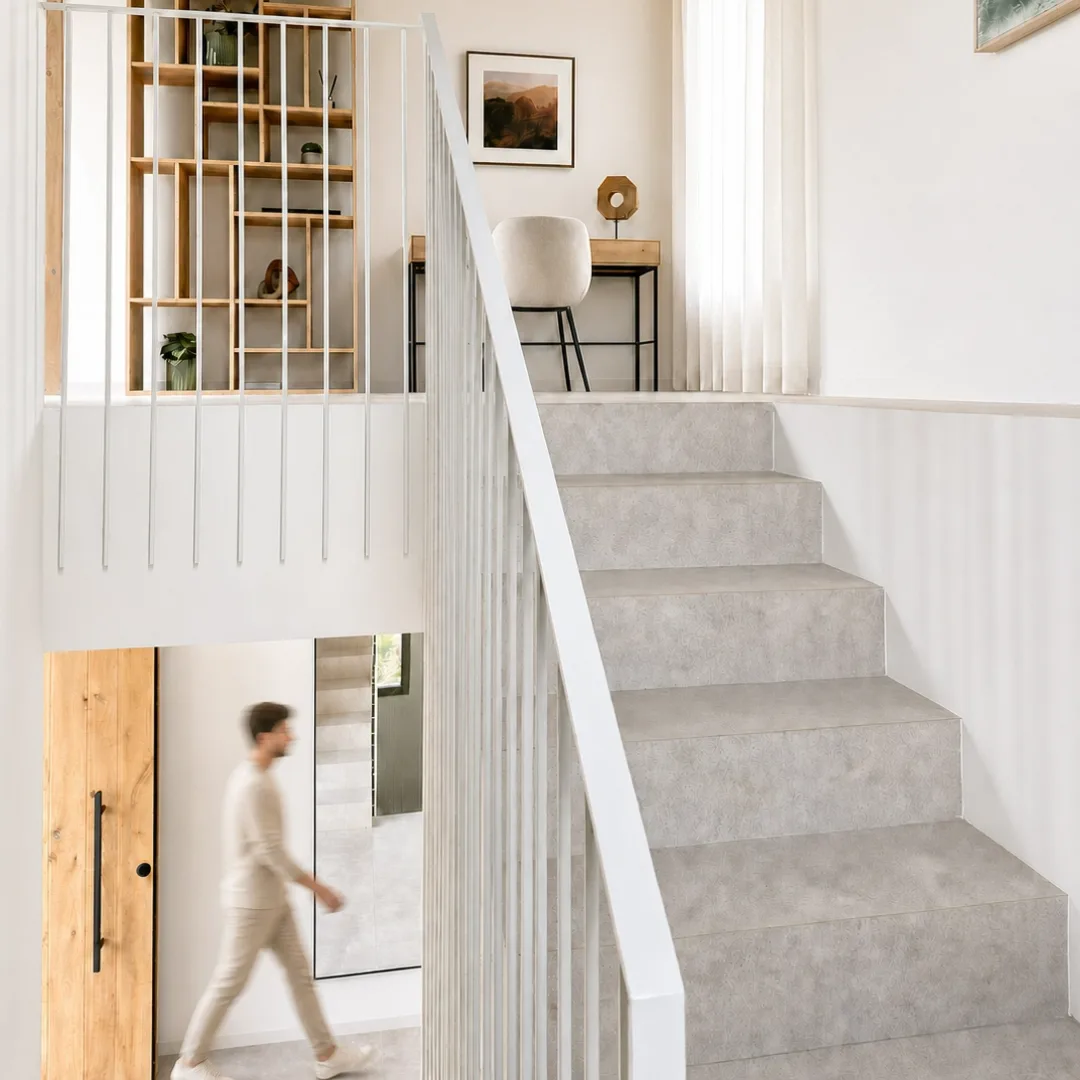Recibidor con escalera de piedra, barandilla blanca y estantería de madera en una vivienda de Sineu