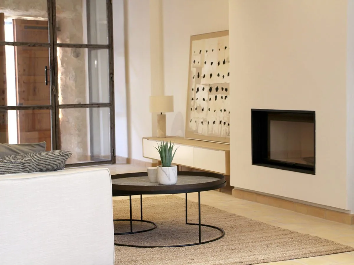 Living room with a fireplace, round coffee table and jute rug in a house in Sineu