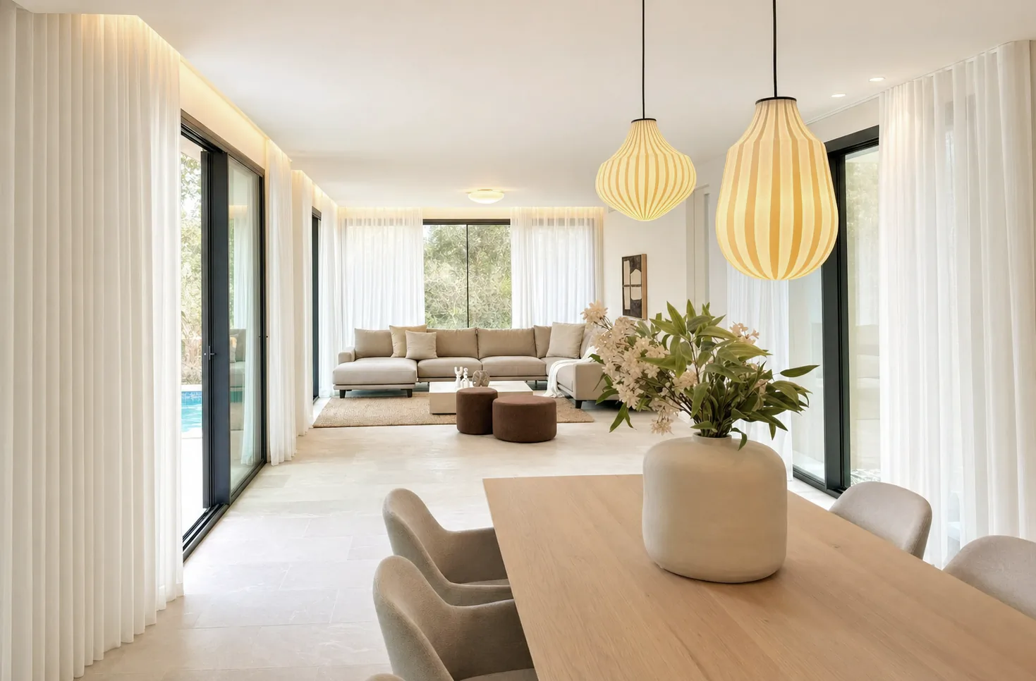 Salón y comedor de la vivienda de Cala Vinyes, con cortinas de lino y grandes ventanales al jardín.