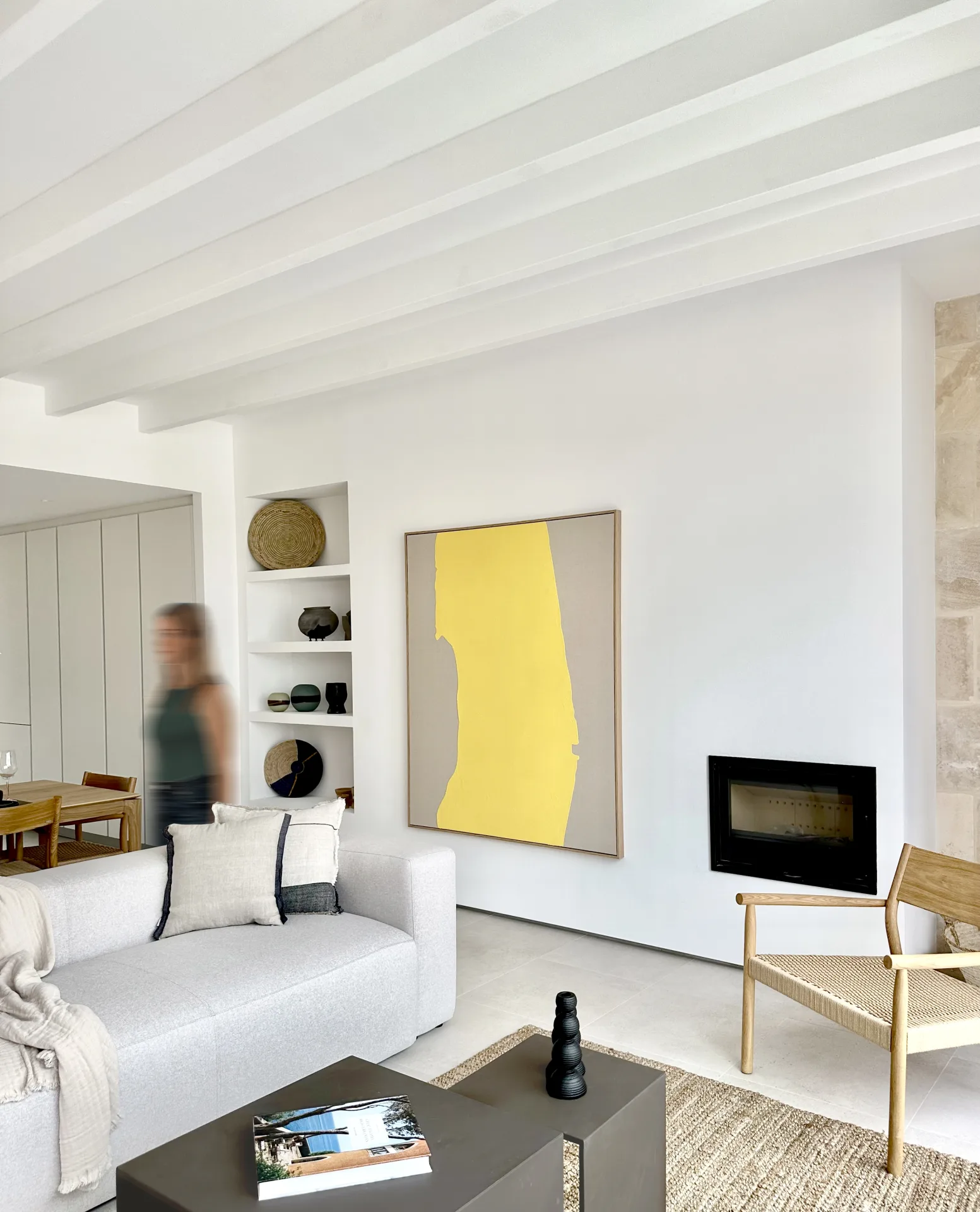 Salón con cuadro amarillo, chimenea y sofá blanco en Ariany