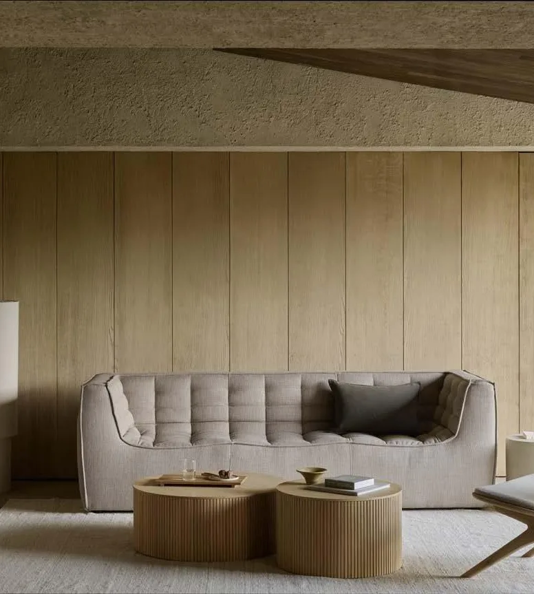 Salón de hotel con sofá modular, mesas de madera y butaca Salón de hotel con sofá modular, mesas de madera y butaca