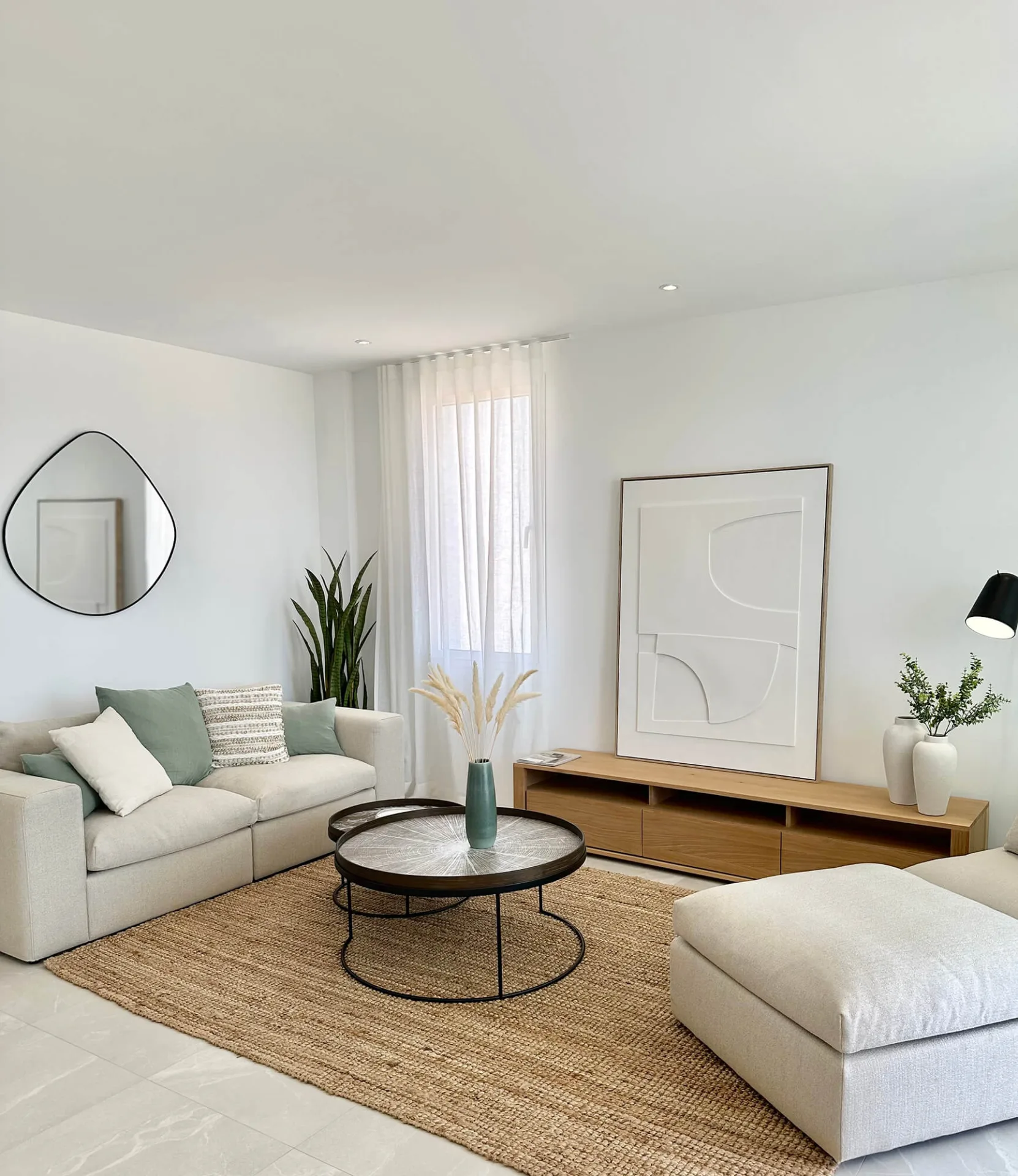 Salón con sofá blanco, alfombra de yute y mesa de centro negra Salón con sofá blanco, alfombra de yute y mesa de centro negra