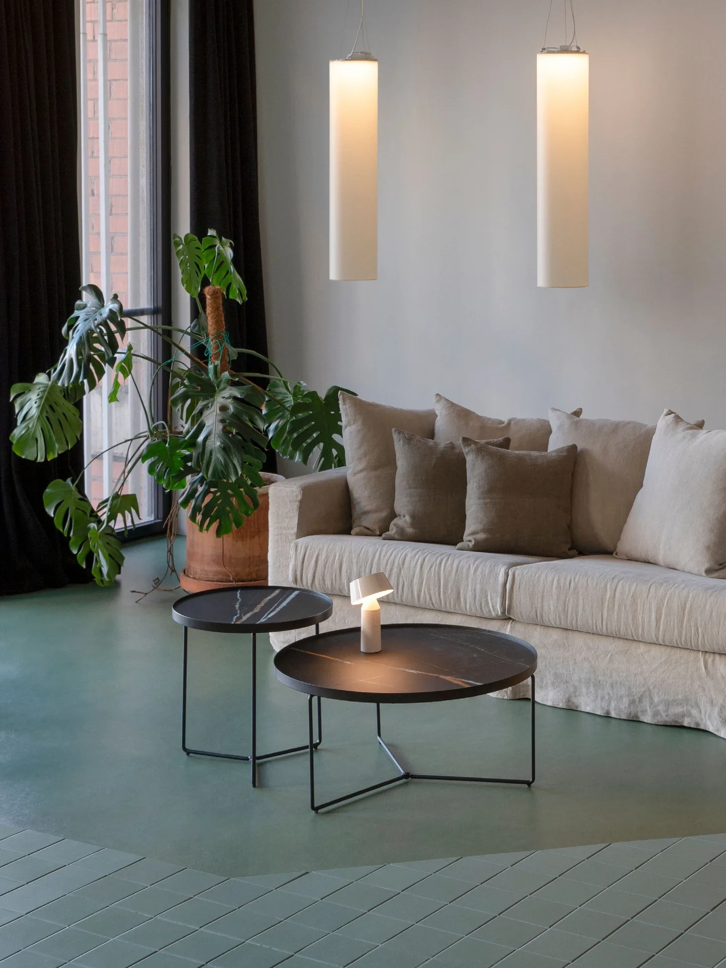 Salón con sofá blanco, mesas de centro metálicas y lámparas de pared