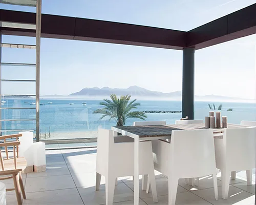 Terrasse mit weißem Esstisch und Blick auf die Bucht von Pollença